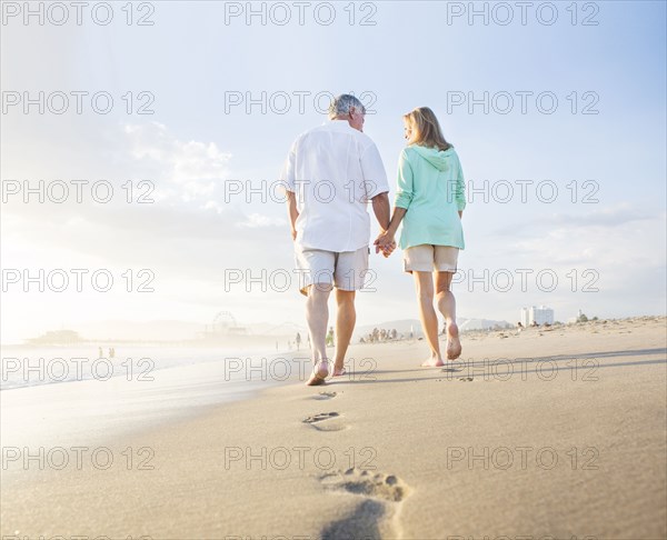 Caucasian couple leaving footprints on beach