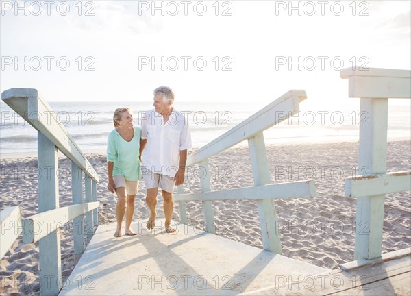 Caucasian couple walking on wooden boardwalk on beach