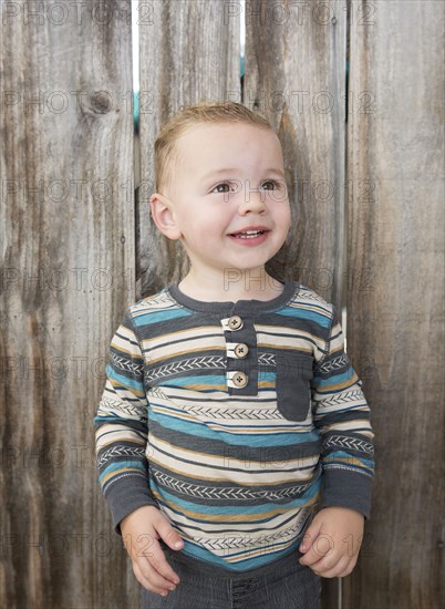 Caucasian boy smiling near wooden fence