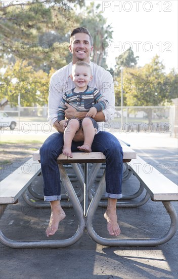 Caucasian father and son sitting on picnic table