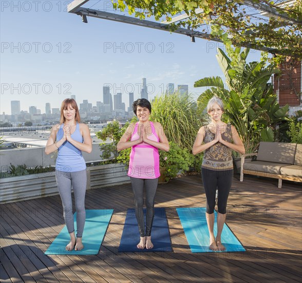 Women practicing yoga together on urban rooftop