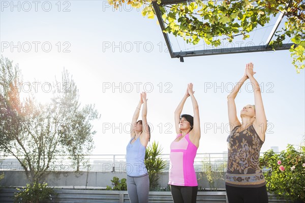 Women practicing yoga together on urban rooftop