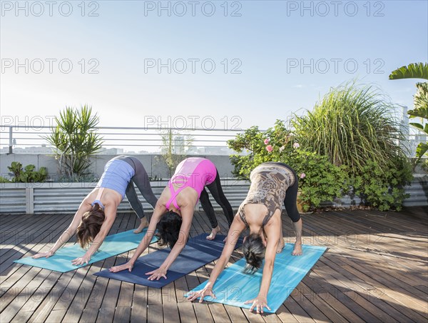 Women practicing yoga together on urban rooftop