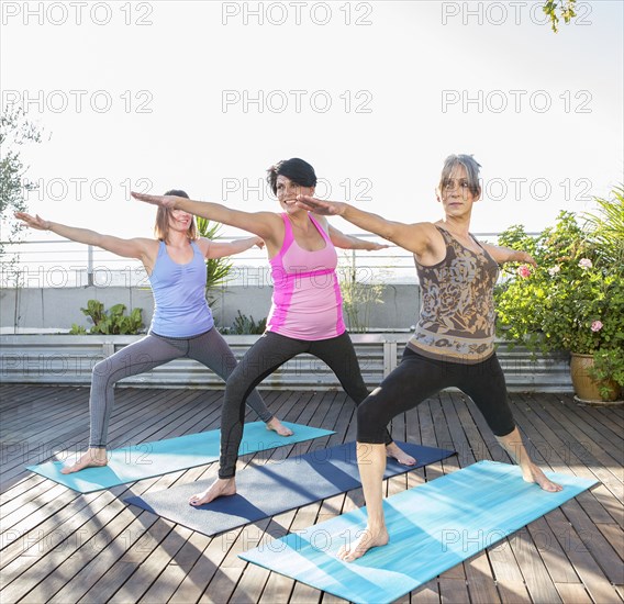 Women practicing yoga together on urban rooftop