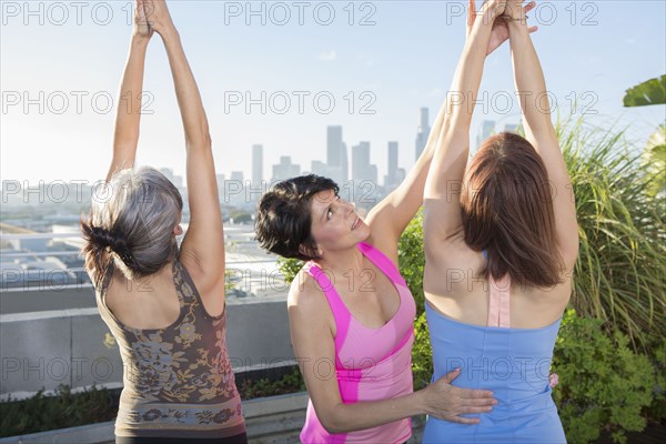 Teacher helping yoga students in class on urban rooftop