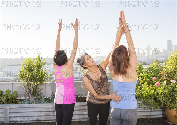 Teacher helping yoga students in class on urban rooftop