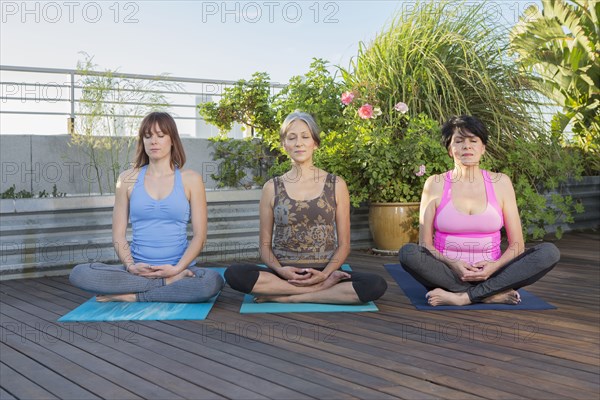 Women meditating together on urban rooftop