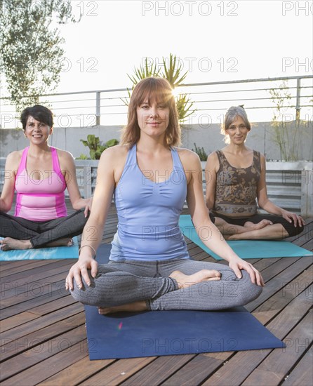 Women sitting on yoga mats on rooftop