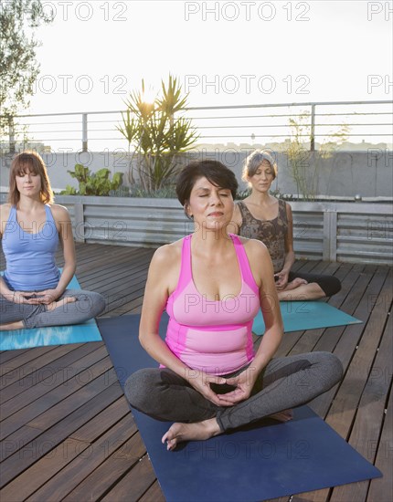 Women meditating on urban rooftop