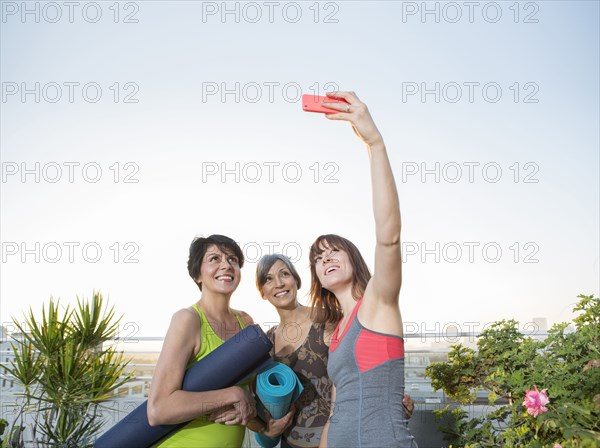 Women taking cell phone selfie on urban rooftop