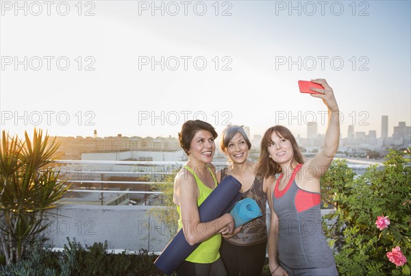 Women taking cell phone selfie on urban rooftop