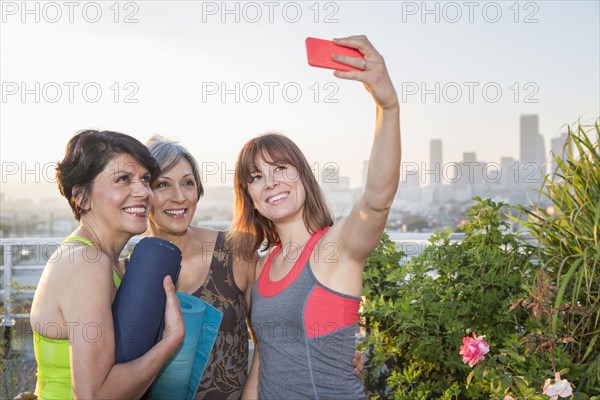 Women taking cell phone selfie on urban rooftop