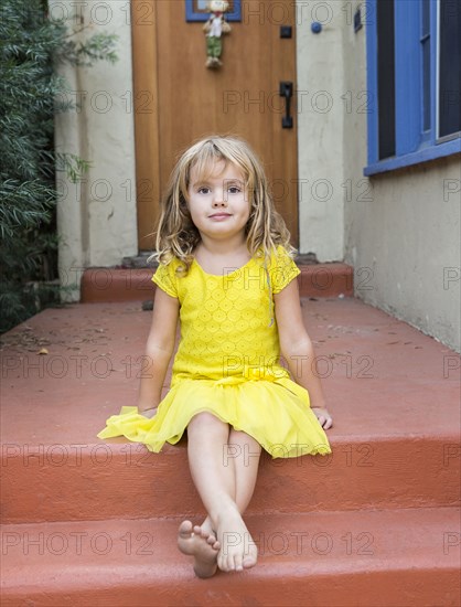 Caucasian girl sitting on front stoop