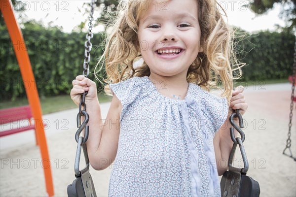 Caucasian girl playing on swing