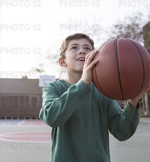 Caucasian boy holding basketball on court