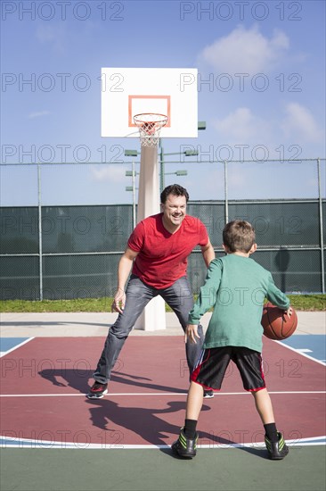 Caucasian father and son playing on basketball court