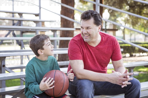 Caucasian father and son talking on bleachers