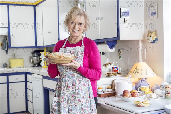 Older Caucasian woman baking pie in kitchen