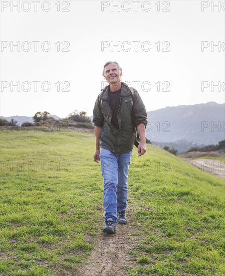 Older Caucasian man walking on dirt trail