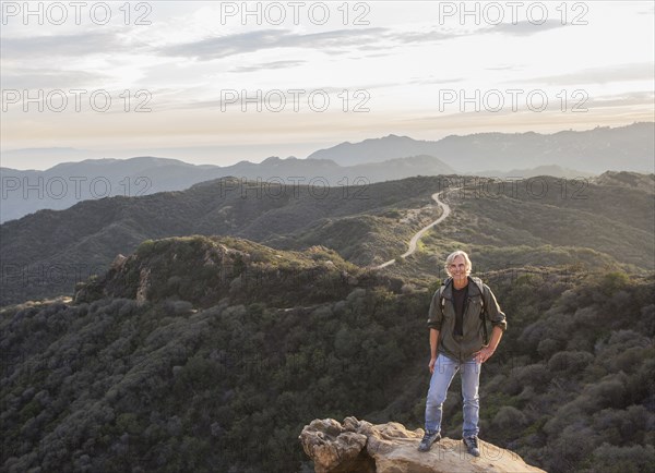 Older Caucasian man standing on rocky hilltop