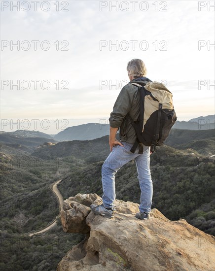 Older Caucasian man standing on rocky hilltop