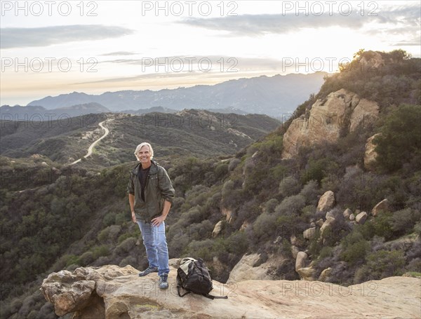 Older Caucasian man standing on rocky hilltop