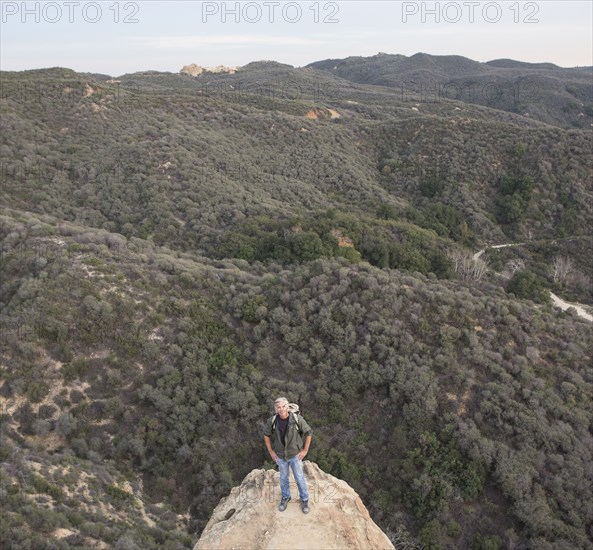 High angle view of older Caucasian man standing on rocky hilltop