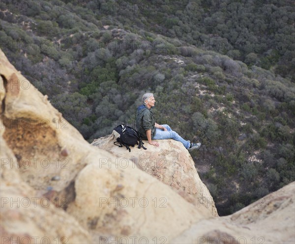 High angle view of older Caucasian man sitting on rock formation