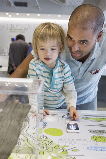 Hispanic father and son using cell phone in museum