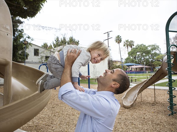 Hispanic father and son playing on playground
