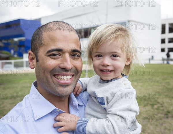 Hispanic father and son smiling in field