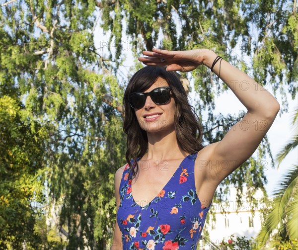 Hispanic woman shielding her eyes from sun