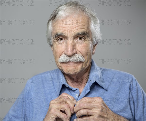 Close up of older Caucasian man buttoning his shirt