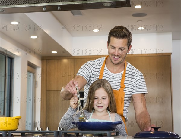 Caucasian father and daughter cooking in kitchen