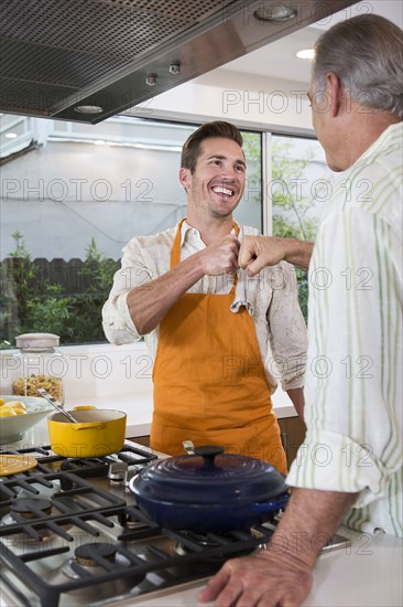 Caucasian father and son fist-bumping in kitchen