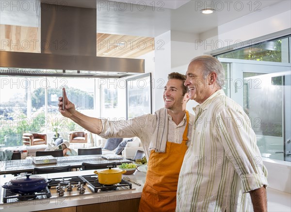 Caucasian father and son taking selfie in kitchen