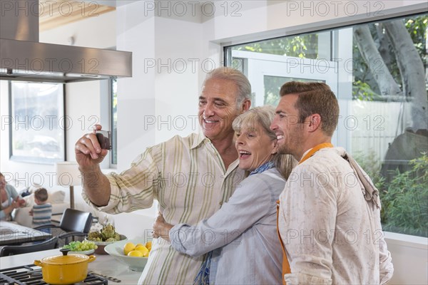 Caucasian parents and son taking selfie in kitchen