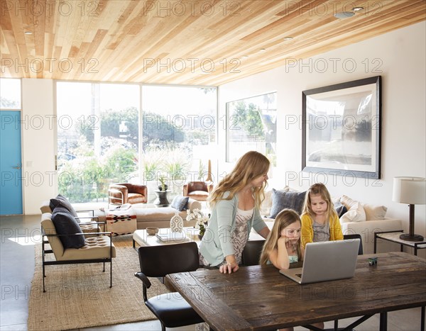 Caucasian mother and daughters using laptop in living room