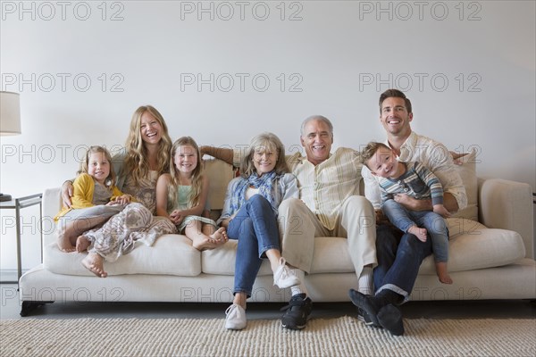 Caucasian multi-generation family sitting on sofa in living room