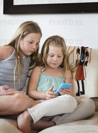 Caucasian girls using cell phone on sofa