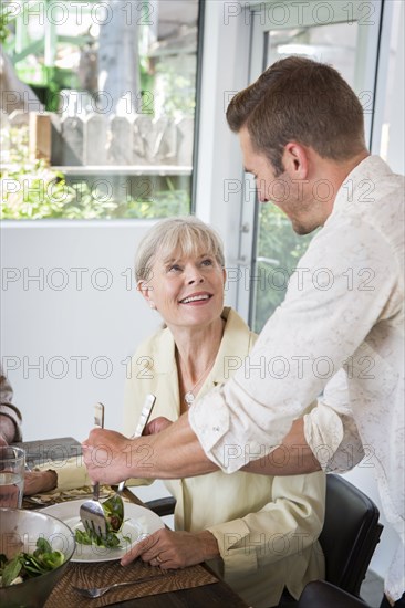 Caucasian man serving mother at table