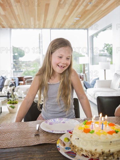 Caucasian girl admiring birthday cake at party