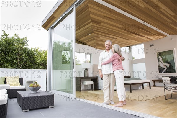 Older Caucasian couple hugging on porch