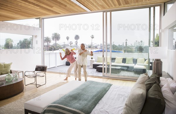 Older Caucasian couple dancing in bedroom