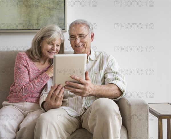 Older Caucasian couple using digital tablet on sofa