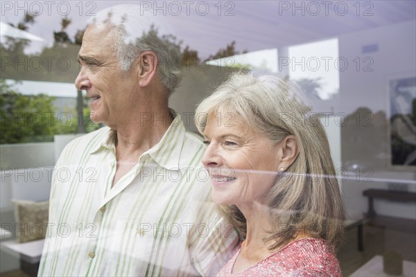 Older Caucasian couple looking out window