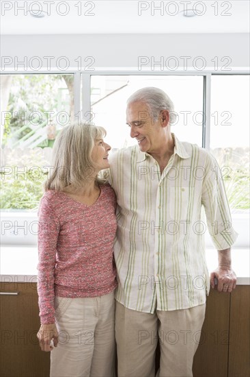 Older Caucasian couple hugging in kitchen