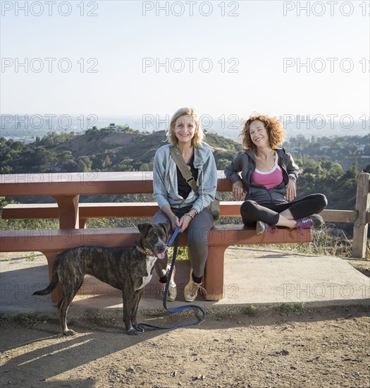 Caucasian women sitting with dog on hilltop