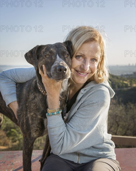 Caucasian woman hugging dog on hilltop