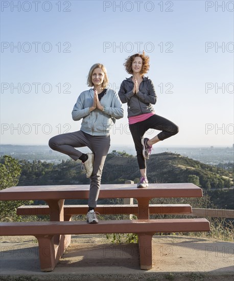 Caucasian women practicing yoga on hilltop